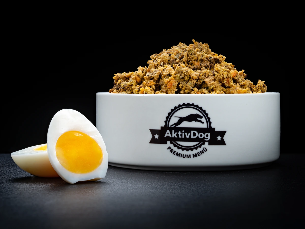 Großaufnahme von AktivDog Hundefutter vegetarisch mit links daneben liegendem aufgeschnittenen Bio-Freilandei