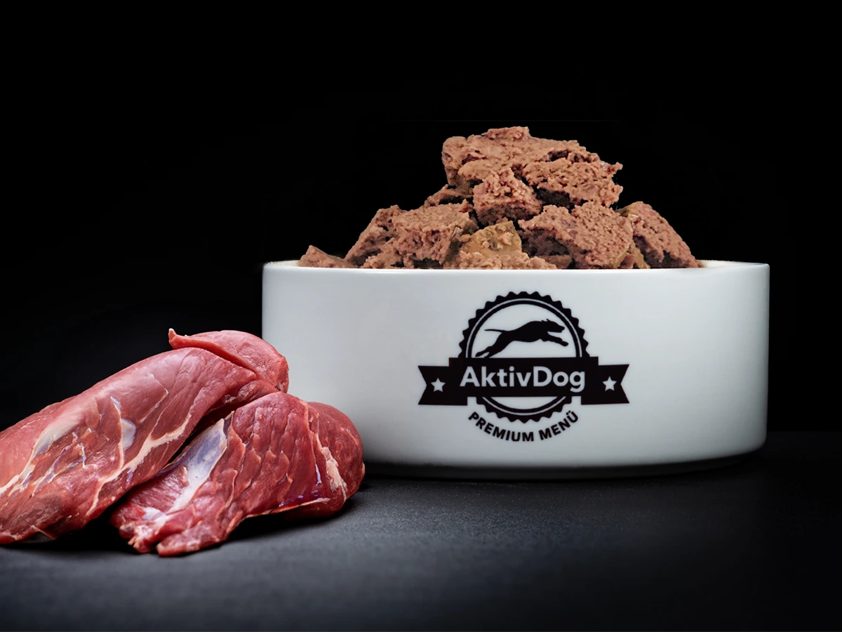 Großaufnahme von AktivDog Hundefutter 100% Wildschwein mit links daneben liegendem rohen Wildschweinfleisch